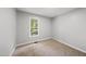 Bright bedroom features neutral carpet, gray walls, white trim, and a window overlooking a green backyard at 6009 Shadow Moss Cir, Raleigh, NC 27603