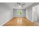 Bright bedroom features hardwood floors, gray walls, ceiling fan, and a window overlooking a green backyard at 6009 Shadow Moss Cir, Raleigh, NC 27603