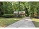Traditional home with a cozy front porch and a long driveway, surrounded by lush greenery and mature trees at 6009 Shadow Moss Cir, Raleigh, NC 27603