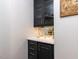 A close-up of a stylish bar area with dark cabinets, glass shelves and a quartz countertop at 612 Peach Orchard Pl, Cary, NC 27519