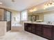 Bright bathroom featuring a double vanity with dark wood cabinets, a soaking tub, and a separate glass-enclosed shower at 612 Peach Orchard Pl, Cary, NC 27519