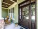 Elegant front porch featuring a dark wood front door, rocking chairs, and green siding at 612 Peach Orchard Pl, Cary, NC 27519