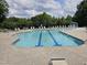A beautiful outdoor pool with clear water, lounge chairs, and a splash pad surrounded by green trees at 612 Peach Orchard Pl, Cary, NC 27519
