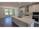 This modern kitchen is designed with a large island, stainless steel appliances, and sleek white cabinets at 659 Bandon Aly, Cary, NC 27513