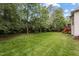Large backyard featuring green grass, tall trees, and a deck at 7 Teahouse Ct, Durham, NC 27707