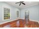 Bright bedroom with hardwood floors, ceiling fan, and natural light from large windows at 7604 Copper Creek Ct, Wake Forest, NC 27587