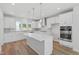 Modern, all-white kitchen boasts stainless steel appliances, quartz countertops, a central island, and stylish pendant lighting at 800 Hillfarm Dr, Wake Forest, NC 27587