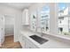 Bright kitchen features white cabinets, quartz countertops, stainless steel sink, and ample natural light from large windows at 800 Hillfarm Dr, Wake Forest, NC 27587
