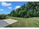 Landscaped backyard with concrete patio, lush trees and grass, and partial fence at 8111 Yaxley Hall Dr, Raleigh, NC 27616