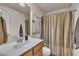 Neutral bathroom features a wood vanity, framed art, and shower with striped curtain at 8111 Yaxley Hall Dr, Raleigh, NC 27616