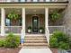 Inviting front porch with brick steps, potted plants, hanging ferns and an ADT security system at 814 Covered Bridge Trl, Chapel Hill, NC 27517