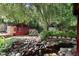 Landscaped backyard featuring a creek, bridge, mature trees, and flowering shrubs at 821 Woodburn Rd, Raleigh, NC 27605