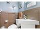 Bathroom with brown tiled wainscoting, light blue walls, toilet, and pedestal sink at 821 Woodburn Rd, Raleigh, NC 27605