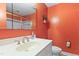 Bright bathroom with a single sink, orange walls, and a glass-enclosed shower/tub at 821 Woodburn Rd, Raleigh, NC 27605