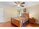 Well-lit bedroom features a ceiling fan, wood floors, and paneled wood bed frame at 821 Woodburn Rd, Raleigh, NC 27605