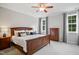 Spacious bedroom with a wooden bed frame, neutral decor, and two windows for natural light at 8909 Tara Hill Ln, Wake Forest, NC 27587