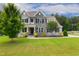 Charming two-story home with stone accents, a well-manicured lawn, and professional landscaping at 8909 Tara Hill Ln, Wake Forest, NC 27587