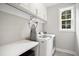 Modern laundry room featuring a stacked washer/dryer, overhead cabinets and an ironing board at 8909 Tara Hill Ln, Wake Forest, NC 27587
