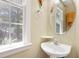 Bright half bathroom with pedestal sink, oval mirror, and a sunlit window at 104 Shady Ridge Ct, Apex, NC 27502