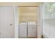 Bright laundry room with full-sized washer and dryer, shelving and natural light from the window at 104 Shady Ridge Ct, Apex, NC 27502