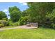 Beautiful backyard featuring a stone patio with a built-in fire pit and seating, surrounded by lush landscaping at 104 Trinity Grove Dr, Cary, NC 27513
