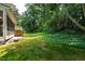 Lush green backyard with lawn, mature trees, and partial view of deck at 115 Heatherwood Dr, Apex, NC 27502