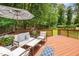 Outdoor deck with a shade umbrella, comfortable seating, and a view of the wooded backyard at 1230 Golden Bluff Ln, Fuquay Varina, NC 27526