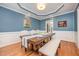 Dining room featuring hardwood floors, wainscoting and a large wooden table set with blue accents at 1230 Golden Bluff Ln, Fuquay Varina, NC 27526
