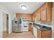 Efficient kitchen with stainless steel refrigerator, oak cabinets, granite countertop and white appliances at 1308 Swallow Dr, Raleigh, NC 27606