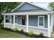 Beautiful blue home with a cozy front porch, white railings, and green lawn at 1318 N Alston Ave, Durham, NC 27701