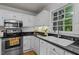 Bright kitchen boasts white cabinets, black granite countertops, stainless steel appliances, and a window with backyard view at 15 Gray Fox Ct, Durham, NC 27713