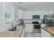 Bright kitchen with butcher block counters, white cabinets, stainless steel appliances, and subway tile backsplash at 169 Forest Dr, Graham, NC 27253