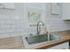 Close-up of the kitchen sink with wood counters, subway tile backsplash, and window with natural light at 169 Forest Dr, Graham, NC 27253