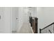 Hallway with dark wood banister leading to the second floor with neutral colored walls and flooring at 187 Harpers Landing Rd, Garner, NC 27529