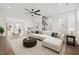 Bright, open-concept living space with a modern ceiling fan, wood floors, and plush white sectional at 209 Timber Forest Ln, Cary, NC 27519
