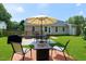 Landscaped backyard with table and chairs under umbrella with a fire pit and barbeque at 212 Southerby Dr, Garner, NC 27529