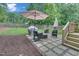Outdoor patio features an umbrella, a grill, and a seating area for entertaining guests in a landscaped backyard at 2310 Turning Pointe Way, Hillsborough, NC 27278