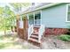 Brick steps lead to the front entrance of this home with light green siding and white trim at 2642 Holly Springs Church Rd, Broadway, NC 27505