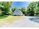 Exterior of home surrounded by lush trees, featuring a backyard deck and spacious gravel driveway at 2642 Holly Springs Church Rd, Broadway, NC 27505