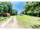 A long gravel driveway leads to property buildings and a verdant grassy field at 2642 Holly Springs Church Rd, Broadway, NC 27505