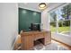Stylish office space with a wooden desk, green accent wall, and natural light from a large window at 2713 Trifle Lane Ln, Wake Forest, NC 27587