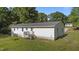 Backyard view of a home features a white exterior, small deck, green grass, and trees at 282 Cooke Rd, Louisburg, NC 27549