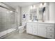 Modern bathroom featuring double vanity, framed mirrors, and glass enclosed shower with gray tiling at 303 Rothbury Ct, Sanford, NC 27330