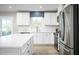 Bright kitchen with white cabinetry, stainless steel appliances, quartz countertops, and stylish light-filled windows at 303 Rothbury Ct, Sanford, NC 27330