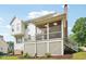 Rear view of a large house with a deck, screen porch, chimney, and brick foundation at 305 Promontory Point Dr, Cary, NC 27513