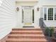 The front entrance displays brick steps leading to a covered porch with elegant lighting at 305 Promontory Point Dr, Cary, NC 27513