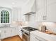 An elegant kitchen features white cabinetry, stainless steel appliances, marble countertops and a window over sink at 305 Promontory Point Dr, Cary, NC 27513