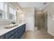 Bathroom with blue vanity featuring white countertop, shower with glass enclosure, and large window at 316 Levi Ln, Wake Forest, NC 27587