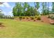 Well-maintained backyard features a tiered landscape design with mature trees and mulch, providing privacy at 33 E Ravano Dr, Clayton, NC 27527