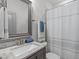 Well-lit bathroom featuring a granite countertop, framed mirror, and shower with a white and grey striped shower curtain at 4105 Bankshire Ln, Raleigh, NC 27603
